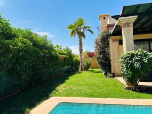 a backyard with a swimming pool and a palm tree at Villa 228 Dyar Shemsi in Taroudant