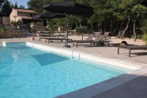 a swimming pool with chairs and umbrellas next to it at Les Chambres du Hameau in Gordes