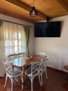 een eettafel met stoelen en een flatscreen-tv bij Casa cómoda y acogedora en San Pedro de Atacama in San Pedro de Atacama