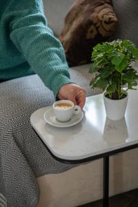a person holding a cup of coffee on a table at Stella & Rosie - Two Bedroom Apartment's by ELDI in Pieta