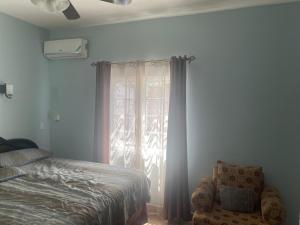 ein Schlafzimmer mit einem Bett und einem Stuhl und einem Fenster in der Unterkunft Le Quad - One Bedroom & Studio Apt - Private, Spacious & Secured in Kingston + 24 Fotos