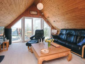 a living room with a leather couch and a coffee table at Panoramic Fjord Retreat with Spa Bath in Øster Assels