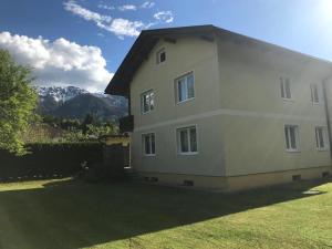 a house in a yard with mountains in the background at Fewos Wuzella Faaker See in Latschach