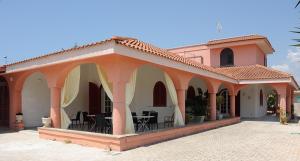 an orange and white building with tables and chairs at Bed & Breakfast Villa Corallo Parcheggio privato in Porto Cesareo
