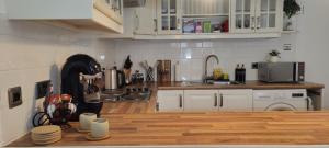 a kitchen with white cabinets and a wooden counter top at Central 1-bed flat - Walk to shops, pubs and station in Saltcoats
