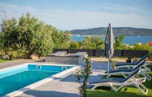 einen Pool mit 2 Liegestühlen und einem Sonnenschirm in der Unterkunft Private Resort Lumianni- 2 Houses in Kaštela