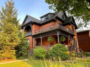 a large red brick house with a black roof at Cozy Coach House in Kitchener