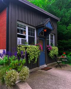 a small house with flowers and a blue door at Cozy Coach House in Kitchener +30 photos
