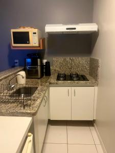 eine kleine Küche mit Herd und Mikrowelle in der Unterkunft Golden Dolphin Gran Hotel in Caldas Novas