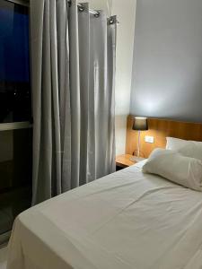 ein Schlafzimmer mit einem weißen Bett und einem Fenster in der Unterkunft Golden Dolphin Gran Hotel in Caldas Novas + 13 Fotos