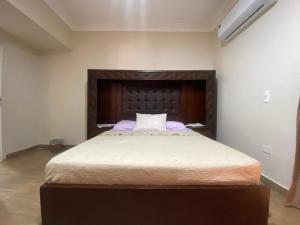 a bedroom with a large bed with a wooden headboard at Comfortable 3BR New Cairo Prime Spot in Cairo