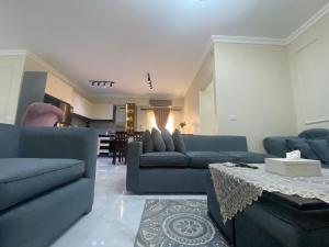 a living room with blue couches and a table at Comfortable 3BR New Cairo Prime Spot in Cairo
