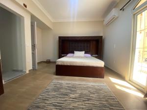a bedroom with a bed and a large window at Comfortable 3BR New Cairo Prime Spot in Cairo