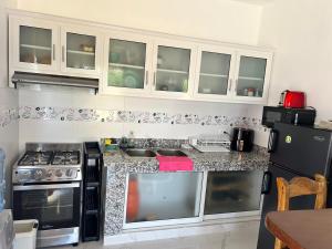 a kitchen with white cabinets and a counter top at Residencia Bambou HAVRE DE PAIX in Juan Dolio