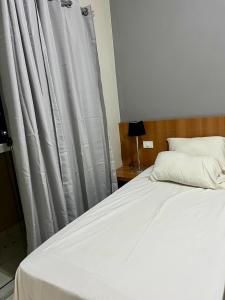 ein Schlafzimmer mit einem weißen Bett und einem Vorhang in der Unterkunft Golden Dolphin Gran Hotel in Caldas Novas