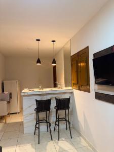 a kitchen with two bar stools and a counter top at Flat mobiliado in Arapiraca