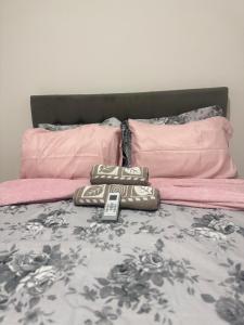 a bed with two pink pillows and a mattress with a remote control at Flat mobiliado in Arapiraca +7 photos