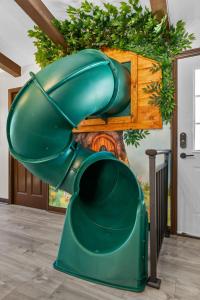 eine grüne Rutsche in einem Zimmer mit einer Wand in der Unterkunft Great Outdoors: Arcade, Golf, Theater, Sauna @more in Garden Grove