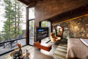 sala de estar con TV y pared de piedra en ESCAPE Hotels & Resorts, en Nathia Gali