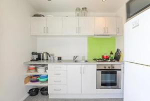 a kitchen with white cabinets and a sink and a refrigerator at Kereru's Nest in Rotorua +20 photos
