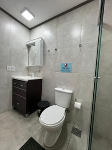 a bathroom with a toilet and a sink and a shower at Steves House Flat Hotel in Puerto Iguazú
