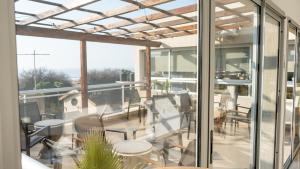 ein Balkon mit Glastüren, Tischen und Stühlen in der Unterkunft Altair Hotel in San Clemente del Tuyú