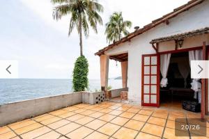 a house with a palm tree next to the ocean at Refúgio a beira Ilha de itacuruça RJ in Ilha de Itacuruçá