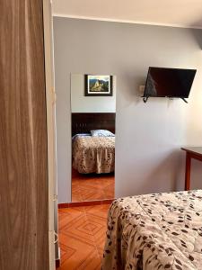 a room with a bedroom with a bed and a television at Hospedaje in Ayacucho +4 photos