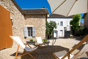 un patio con 2 sillas, una mesa y una sombrilla en Clos Saint Jacques - Maison d'Hôtes, en Meursault