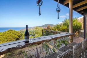 a bottle of wine and two wine glasses on a deck at Ocean Views 20kms from CBD Sleeps 10 in Kingston Beach +25 photos