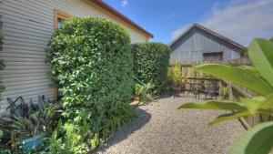 a large green hedge next to a building at Village Stays Bungalow and Apartment in Ulmarra