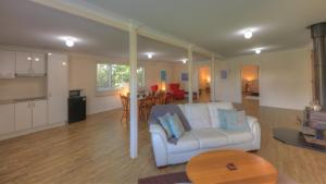 a living room with a white couch and a kitchen at Village Stays Bungalow and Apartment in Ulmarra
