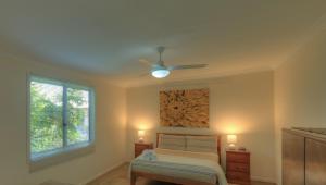 a bedroom with a bed and a ceiling fan at Village Stays Bungalow and Apartment in Ulmarra