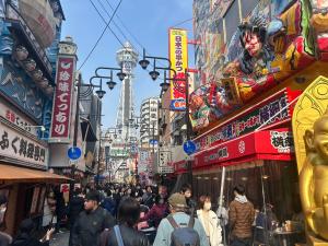 a crowd of people walking down a busy city street at 藤通天阁景观民宿 in Osaka