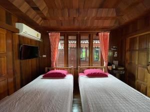 two beds in a small room with pink pillows at Healing House Holistic Farm Stay in Ban Wet