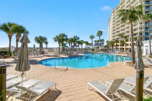 a swimming pool with chairs and umbrellas and a building at Doral 103 - Charming Beachfront / Ground Floor Condo! in Gulf Shores
