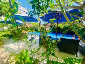 a pool with umbrellas and people in the water at Solaluna Beach Homestay in Amed