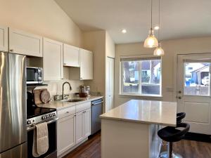 a kitchen with white cabinets and a stainless steel refrigerator at Darling Downtown Cottage - summer in CDA! in Coeur d'Alene