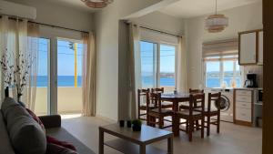Una sala de estar con una mesa y sillas y el océano. en Lily of Crete 1 - Sea & Beach front Apartment, en Kalamaki