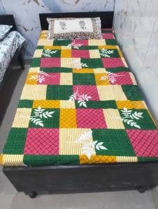 a bed with a colorful quilt on top of it at श्री कृष्णा होम स्टे in Vrindāvan +9 photos