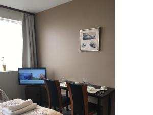 a dining room with a table with chairs and a television at North Star Apartments Rif in Snæfellsbær