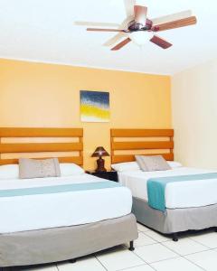 two beds in a room with a ceiling fan at Hotel Reynieri in Comayagüela