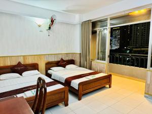 a hotel room with two beds and a window at Tuệ Tĩnh in Nha Trang