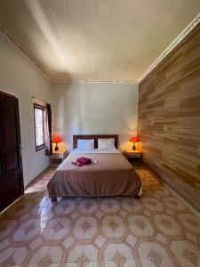 a bedroom with a bed and two lamps on two tables at Satria Bungalow in Uluwatu