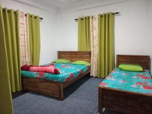 two twin beds in a room with green curtains at Sayst home in Nikawatawana