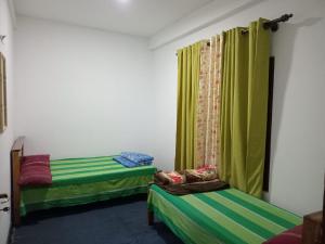 two beds in a room with green curtains at Sayst home in Nikawatawana