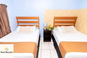 two beds sitting next to each other in a room at Hotel Reynieri in Comayagüela