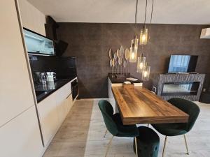 a kitchen with a wooden table and green chairs at Moderný 1 izbový apartmán v Ružinove in Bratislava
