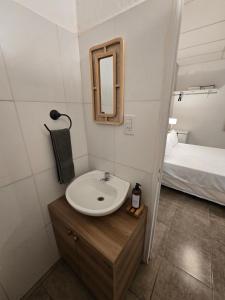 een badkamer met een wastafel en een spiegel en een bed bij El Quebracho, Suites y Apartments in Corrientes +1 foto