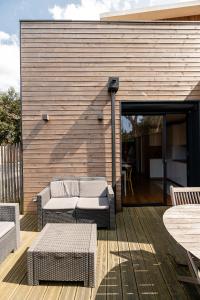 a patio with a couch and tables on a wooden deck at Villa Cocoon Contis océan à 900m in Lit-et-Mixe